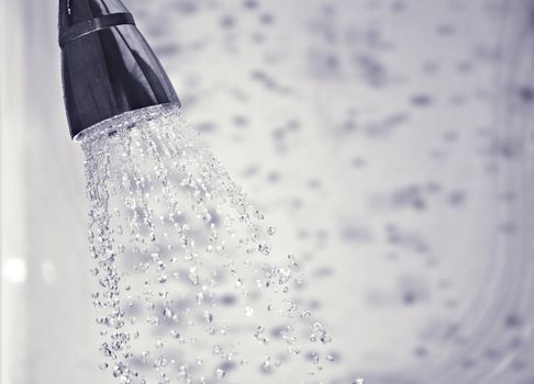 Water comming out of shower head with shadows of the droplets in the background