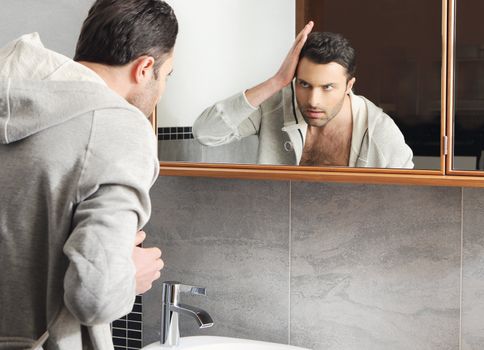 Young man looks at himself in the mirror
