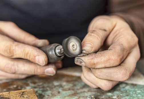 Close-up of the hands of a jeweller polishing a piece of silver.
