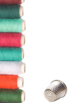 spools of thread and thimble for sewing on white background