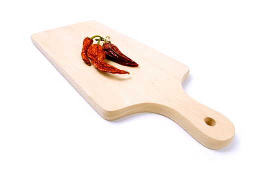 Dried-up red paprika on kitchen board. Isolated on white.