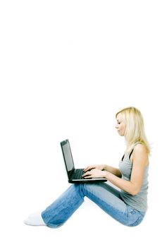 A studio shoot of a beautiful young girl sitting with a computer in her lap.