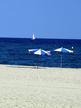 Parasols on a beach with boat in background.