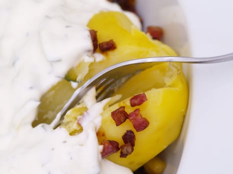 herbs-flavoured curd and bacon on potatoes