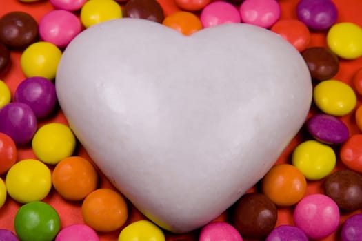 White heart (ginger cake) on red background with drops.