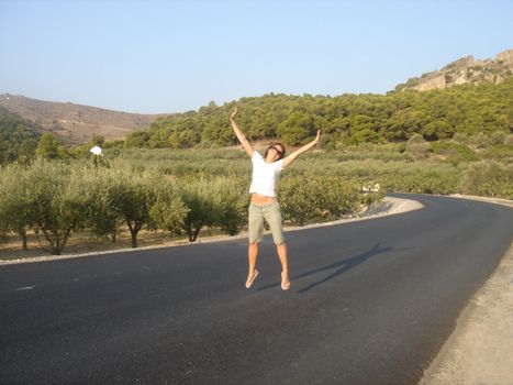 Pretty girl is jumping on countryside road                               