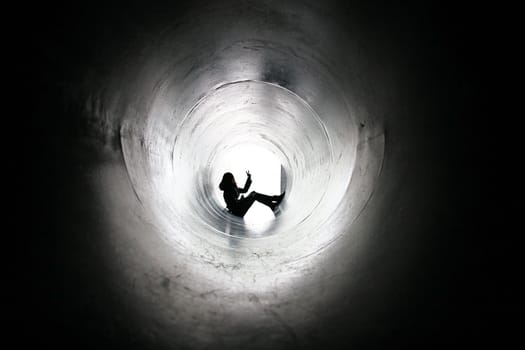 Silhouette of a girl in a big pipe