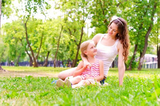 mother and daughter sitting together on the grass, and spend time with family