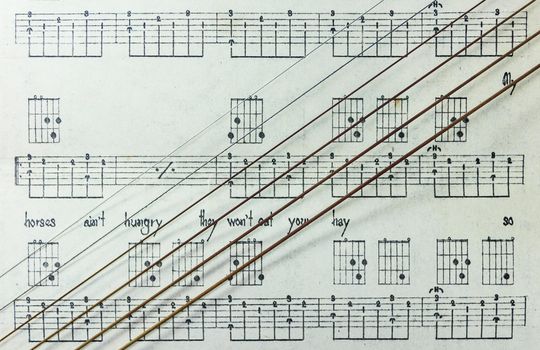 Guitar Strings on Old Yellowed Music Sheet with Lyrics, Closeup