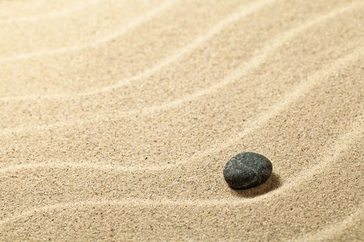 Sandy beach background with black stone. Sand texture