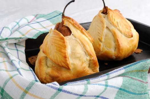 Baked pears stuffed with a mixture of nuts and raisins in the dough