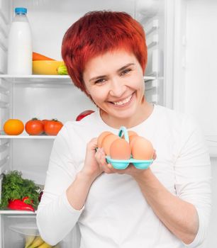 young smiling woman with apples against the refrigerator with food