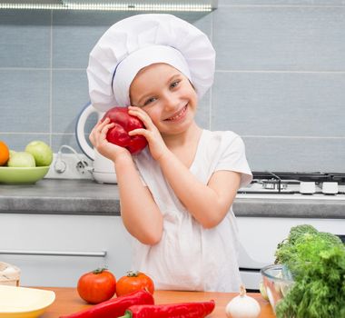 little girl in a cap chef in the kitchen with Pepper