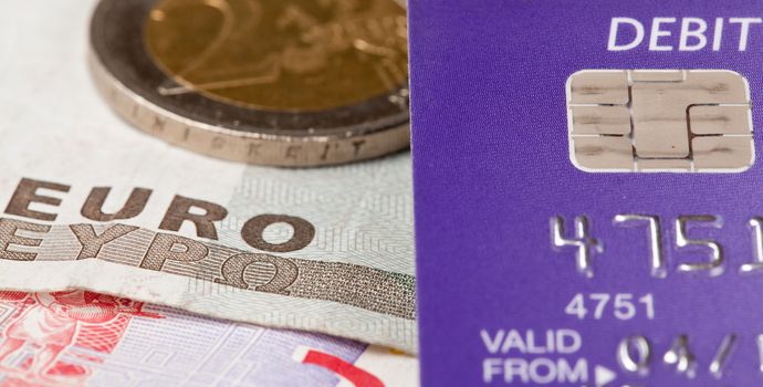 Macro of debit card and on top of euro note to illustrate currency crisis in Europe