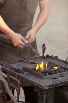 embers, fire, smoke, tools and the hands of a blacksmith