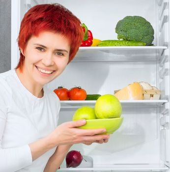 young woman with apples against the refrigerator with food