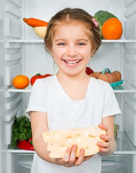 little girl with cheese against a refrigerator with food