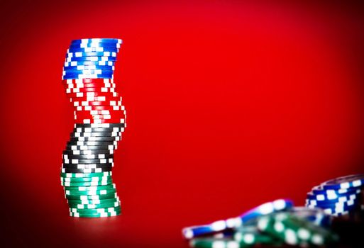 stacks chips for poker on red table with place for text