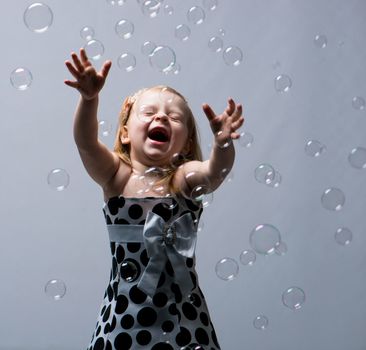 cute little girl with soap bubbles in studio