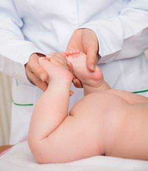 Doctor massaging little baby's foot