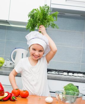 little girl in a cap chef in the kitchen with dill
