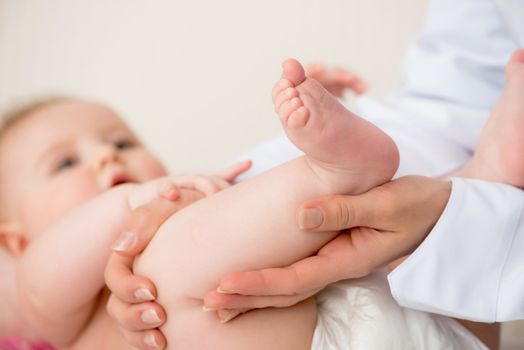 Doctor's hands massaging little baby's legs