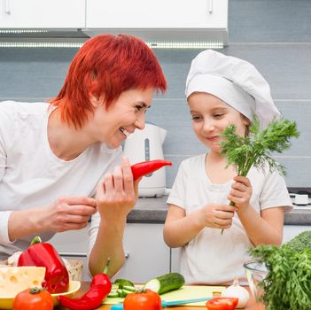 Smiling Mother and daughter in the kitchen with vegetables