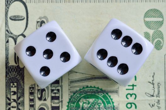 Closeup of a pair of dice with eleven showing on a fifty dollar bill.