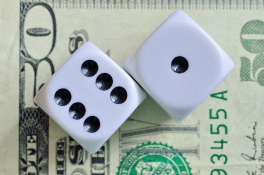 Closeup of a pair of dice with seven showing on a fifty dollar bill.