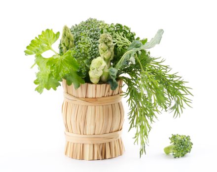 Bouquet of broccoli, asparagus, dill, parsley in wicker basket isolated on white background