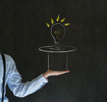Business man, student or teacher pulling idea from a magic hat on blackboard background