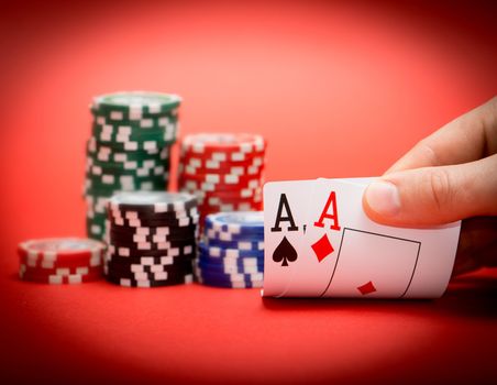 Stack of chips and two aces on a red poker table