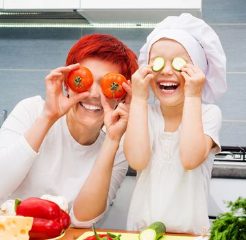 Mother and daughter playing in the kitchen with vegetables