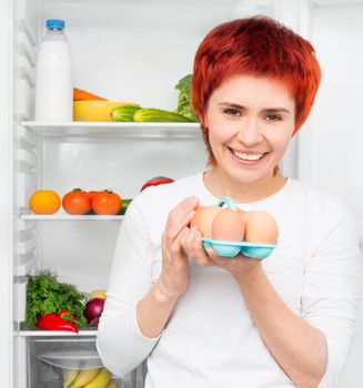 young woman with apples against the refrigerator with food