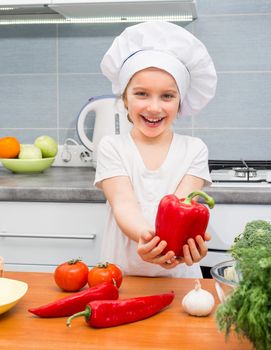 little smiling girl in a cap chef in the kitchen with Pepper