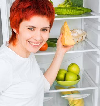 young woman with apples against the refrigerator with food