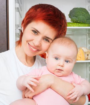 Mother and baby in the kitchen with vegetables