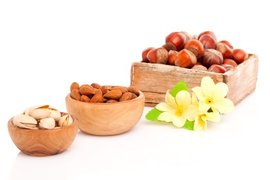 Pistachio, almonds, hazelnut with flowers in the wooden bowl.