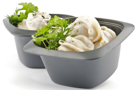 Meat pelmeni with sour cream and greens in black bowls isolated on white background