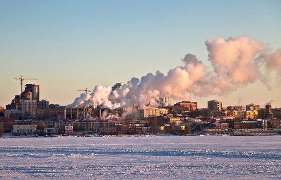 Heat Thermal station is on the shore of the frozen of the river in Samara. Against the backdrop of the sunset light and the sky. Out of the smoke pipe is. Samara. Russia.
