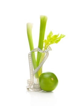 celery in a tall glass, green grapefruit and measure tape isolated on white