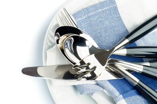 Arrangement of Silverware with Table Knife, Table Spoon, Fork, Dessert Spoon and Dessert Fork on Blue Napkin closeup. Top View