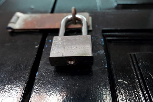 Big metal lock on black wooden door