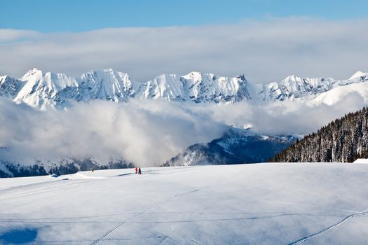 Panoramic View on Mountains and Two People Trekking in French Alps in Winter