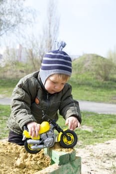boy playing with a toy in warm clothing and cap