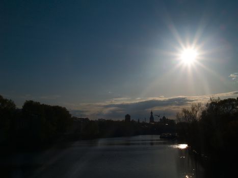 Sunset in the small town. Silhouette view of embankment and star view of sun