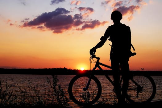 Silhouette of a cyclist admiring the sunset.