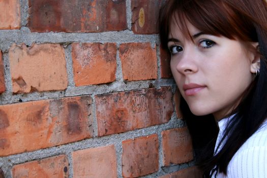 Girl leaning against a red brick wall