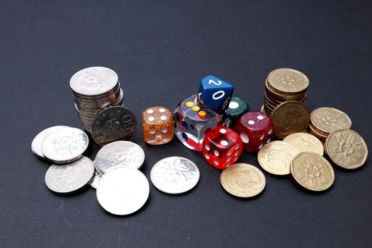 6 coloured dices with coins on dark background