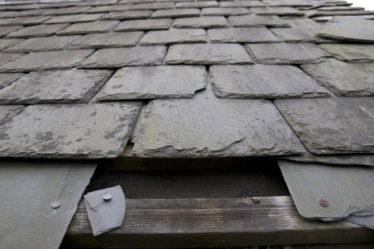 broken and fallen slate leaves hole in a roof due to storm or decay